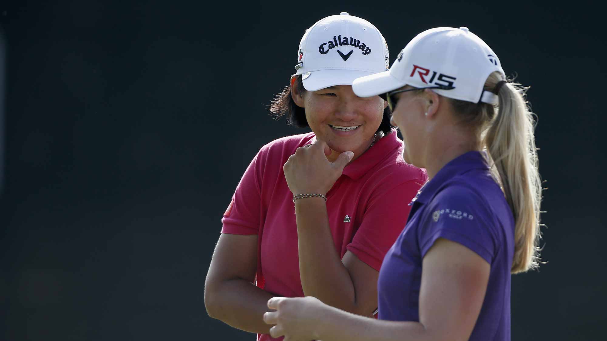 Yani Tseng of Taiwan talks to Austin Ernst before putting on the 18th hole during the final round of the Yokohama Tire LPGA Classic at the Robert Trent Jones Golf Trail at Capitol Hill 