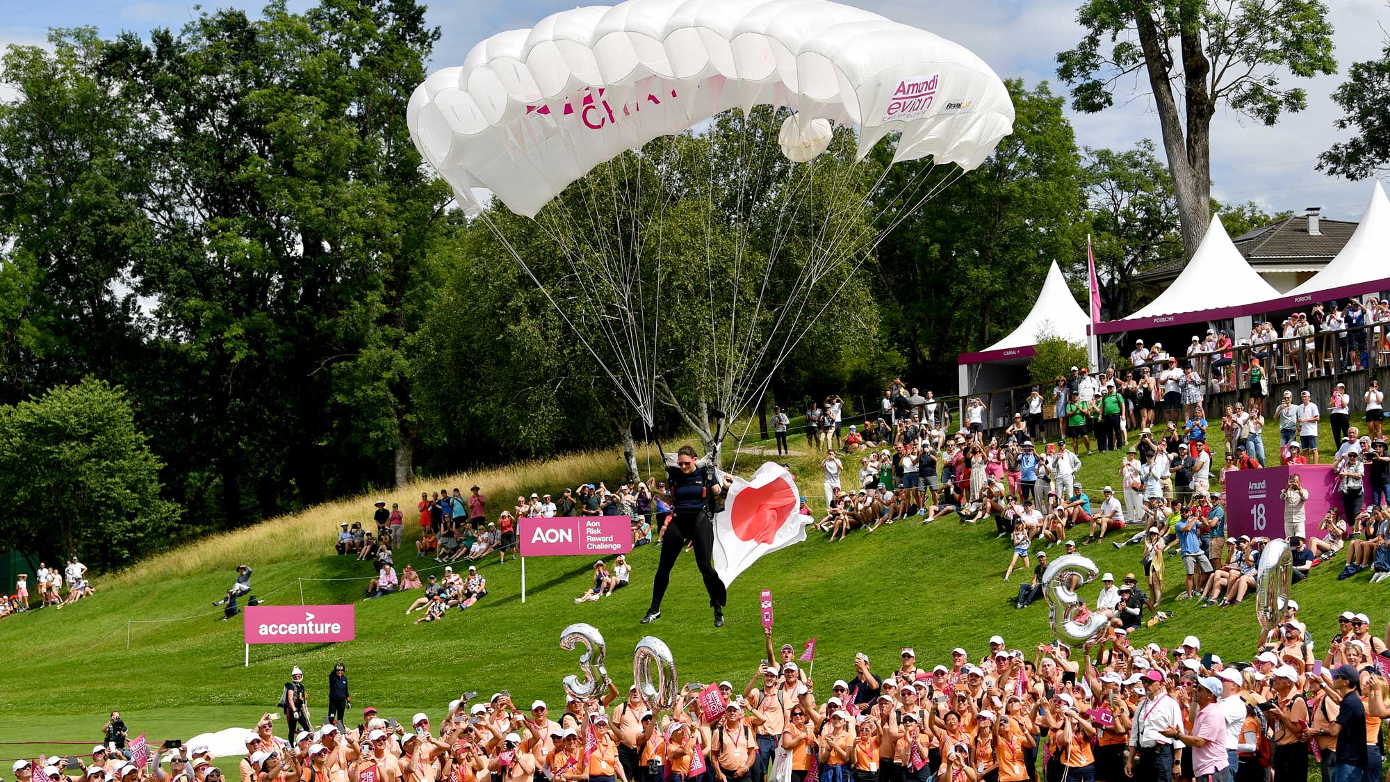 Parachuter handles the Japanese flag to Ayaka Furue during the final round of the Amundi Evian Championship at Evian Resort Golf Club on July 14, 2024 in Evian-les-Bains, France.